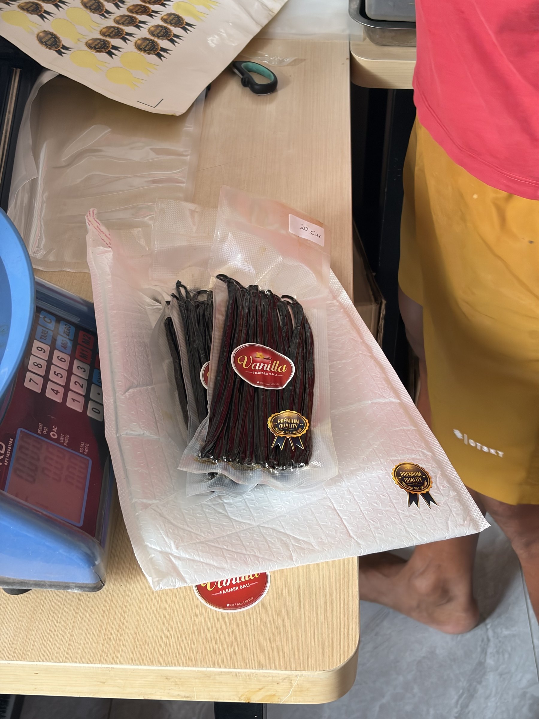 Sealed bags of vanilla beans with red stickers ready on the work table