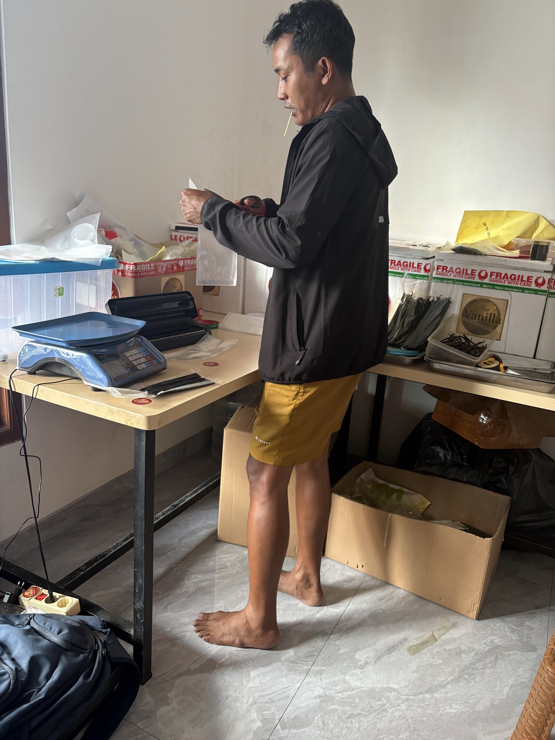 Gustu packing vanilla beans at his work table